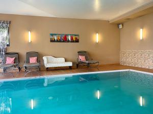 a pool in a hotel room with chairs and a couch at Wittenbeck Resort in Kühlungsborn