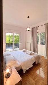 duże białe łóżko w pokoju z oknami w obiekcie Key Biscayne Elegant 77sqm apt in Paleo Faliro w Atenach