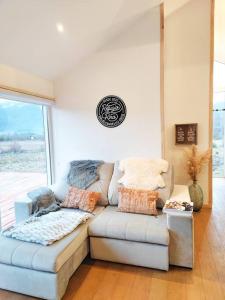 sala de estar con sofá y ventana en Confortable refugio de monataña con vista al Volcan, en Malalcahuello