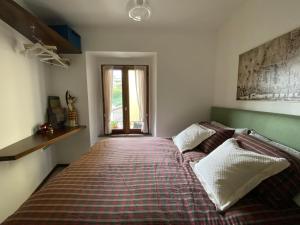 ein Schlafzimmer mit einem Bett mit einer Decke und einem Fenster in der Unterkunft Dagli Olivari - Casa Teo in Gromo