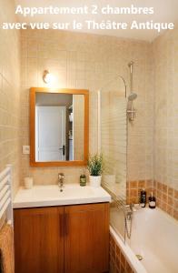 uma casa de banho com um lavatório, uma banheira e um espelho. em Holiday in Arles -Appartement du Théâtre Antique em Arles