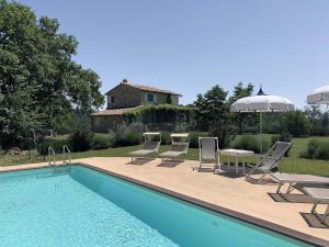 een zwembad met stoelen, een tafel en een parasol bij La Campanina in Capanne