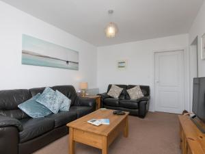 a living room with a black leather couch and a tv at Pass the Keys Spectacular Sea View Apartment with free Parking in Trearddur