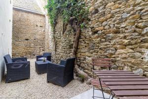 un patio con sillas, una mesa y una pared de piedra en Le Pigalle, en Nolay