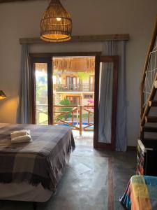 1 dormitorio con 1 cama y puerta que da a un patio en Pousada Rosa dos Ventos Lagoinha, en Lagoinha
