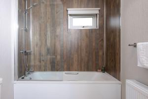 eine Badewanne im Bad mit Fenster in der Unterkunft Daisy Lodge, 6 Roadford Lake Lodges in Lifton + 17 Fotos