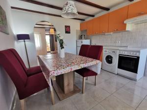 a kitchen with a dining room table and red chairs at Guesthouse Stivan (920) in Štivan