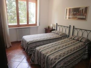 dwa łóżka w pokoju z oknem w obiekcie Casa vacanza montecapino w mieście Chiusdino