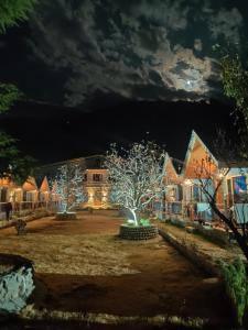 a house with a tree in the yard at night at Winterfell The Stay, Unique River Front Resort in Manāli