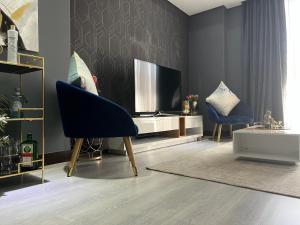 Luxury Apartment - Michelangelo Towers في جوهانسبرغ: غرفة معيشة مع تلفزيون وكرسيين