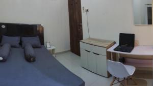 a bedroom with a bed and a desk with a laptop at Choko Homestay in Tjolomadu