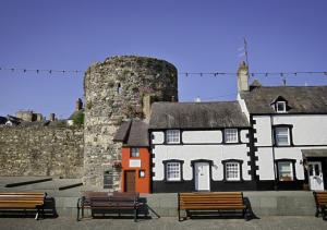 a building with benches in front of a castle at Naw Stryd y Capel in Conwy