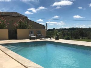 a swimming pool with two chairs next to a house at gites de la Vaysse in Vergt-de-Biron +17 photos