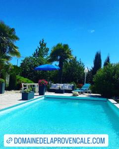 a swimming pool with a blue umbrella and chairs at Domaine de la Provençale in Saint-Didier-de-la-Tour