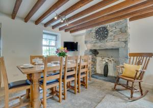 a dining room with a table and a stone fireplace at Maes y Llan in Caernarfon