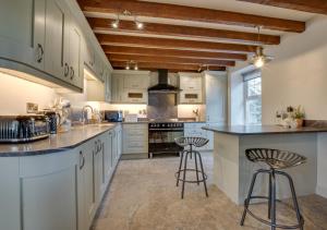 a kitchen with white cabinets and a large island with bar stools at Maes y Llan in Caernarfon