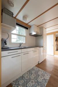 una cucina con armadi bianchi e un tappeto di 87, gelegen in het rustige & bosrijke Oisterwijk! a Oisterwijk