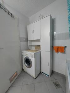- un lave-linge et un sèche-linge dans une cuisine avec une armoire blanche dans l'établissement Xenia apartments, à Belgrade