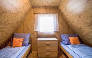two beds in a wooden cabin with a window at Gorgeous Home In Jedwabno With Kitchen in Jedwabno