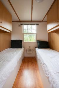 2 camas en una habitación pequeña con ventana en 87, gelegen in het rustige & bosrijke Oisterwijk!, en Oisterwijk