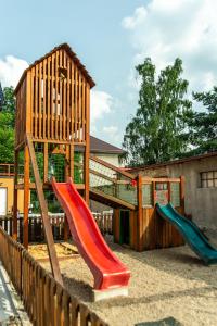 um parque infantil com escorregas e uma estrutura de jogos de madeira em Penzion La Piccolina em Nový Bor