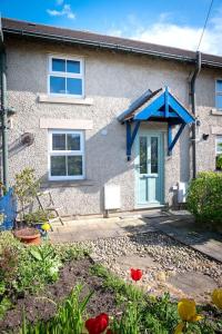una casa con una puerta azul y flores delante de ella en Quiet 2 Bedroomed Cottage, near the Lakes en Carnforth