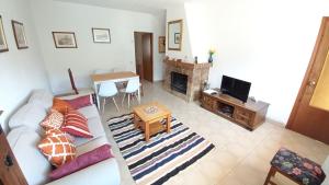 a living room with a white couch and a tv at Casa Rural Alameda con chimenea y jardín in El Barco de Ávila