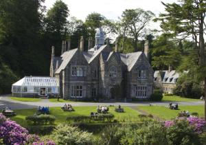 an old house with people sitting in the yard at Lletyr Plas in Llanbedrog