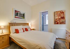 a bedroom with a large white bed with red pillows at Lletyr Plas in Llanbedrog