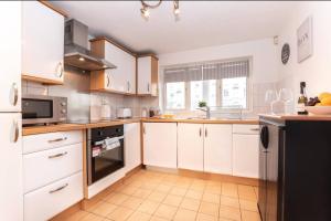 a kitchen with white cabinets and a black refrigerator at Citrine - 2 Bed Apartment With Parking in Reading