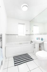 a white bathroom with a tub and a sink at Citrine - 2 Bed Apartment With Parking in Reading