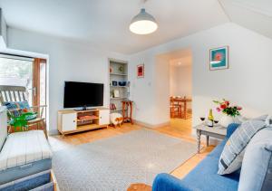 uma sala de estar com um sofá azul e uma televisão em Cwt y Bugail em Pentraeth