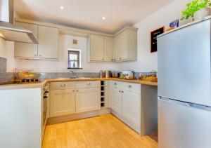 a kitchen with white cabinets and a white refrigerator at Cwt y Bugail in Pentraeth