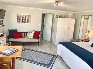 a bedroom with a bed and a couch and a table at C-Pampoentjie in Struisbaai