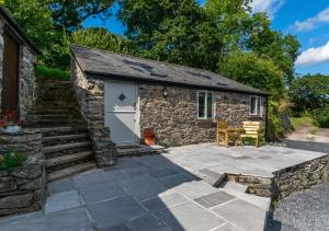 a stone cottage with a patio and stairs to it at Cwt Bach in Llanfair Talhaiarn