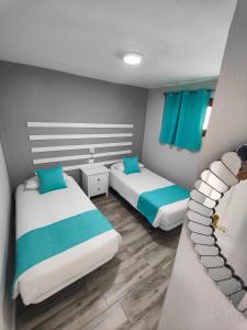 deux lits dans une chambre avec du bleu et du blanc dans l'établissement Apartamentos Australia, à Playa del Ingles