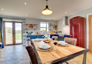 a kitchen with a wooden table with chairs and a red refrigerator at Cwrt y Llyn in Pen-y-groes