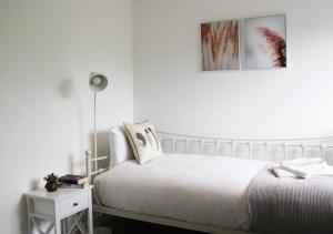 a white bedroom with a white bed and a night stand at Oxford - Private House with Garden & Parking 14 in Yarnton