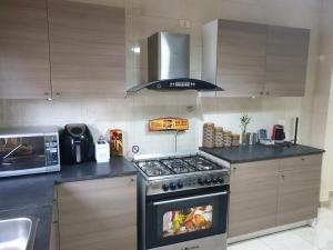 a kitchen with a stove and a microwave at Dair Ghbar 2-bedrooms unit in Amman