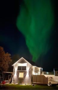 una casa con le luci verdi del nord nel cielo di Sauna House ad Andenes