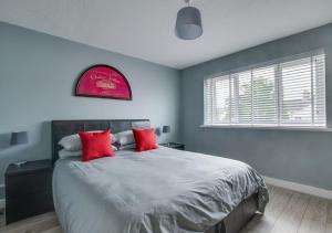 - une chambre avec un grand lit et des oreillers rouges dans l'établissement Taff Penfro Cardiff Apartment, à Cardiff