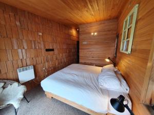 1 dormitorio con 1 cama en una pared de madera en Hotel & Café Bauda, en Castro