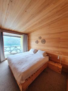 un letto in una camera in legno con una grande finestra di Hotel & Café Bauda a Castro