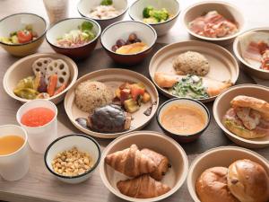 einen Tisch mit Schalen verschiedener Arten von Lebensmitteln in der Unterkunft Super Hotel Premier Ikebukuro Natural Hot Spring in Tokio