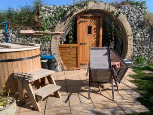 a patio with a chair and a table and a building at Romantic escape luxury Hobbit house with Hot tub! in Sheerness