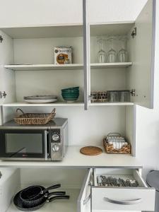 a kitchen with white shelves and a microwave at RANGUEIL - Studio confortable proche hôpital et université in Toulouse