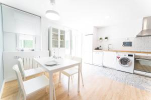 a white kitchen with a white table and chairs at Apartamento Balbín II in Gijón
