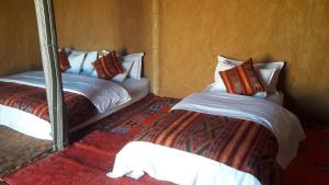 1 dormitorio con 2 camas y espejo en SaharaTime Camp en Hassilabied