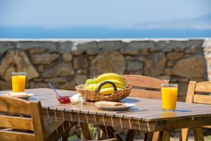 una mesa de madera con una cesta de plátanos y zumo de naranja en Villa-7Days, en Agkidia