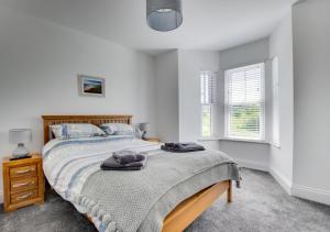 a bedroom with a bed and two windows at Llety Celyn - The Hollies in Cross Hands